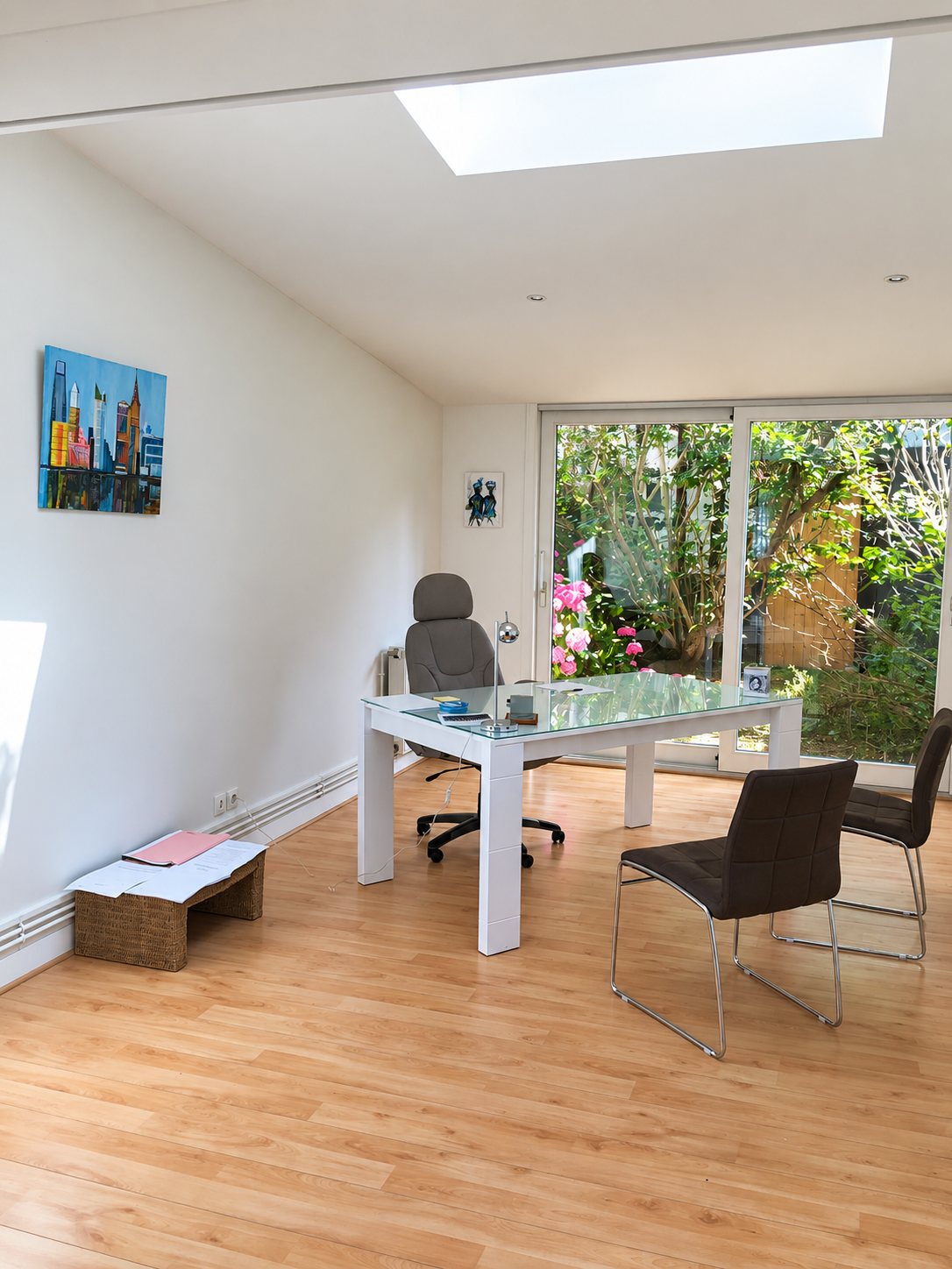 Bureau lumineux avec table en verre et vue sur jardin fleuri